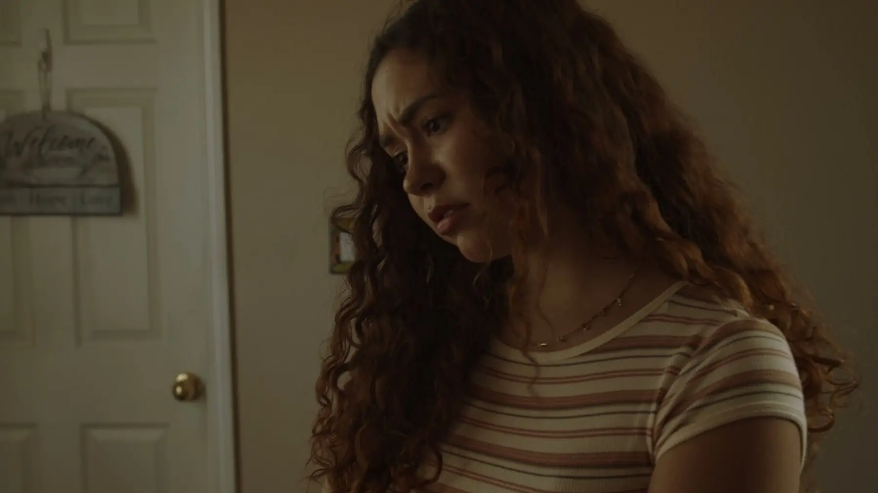 Bria looks downward pensively in a warmly lit room